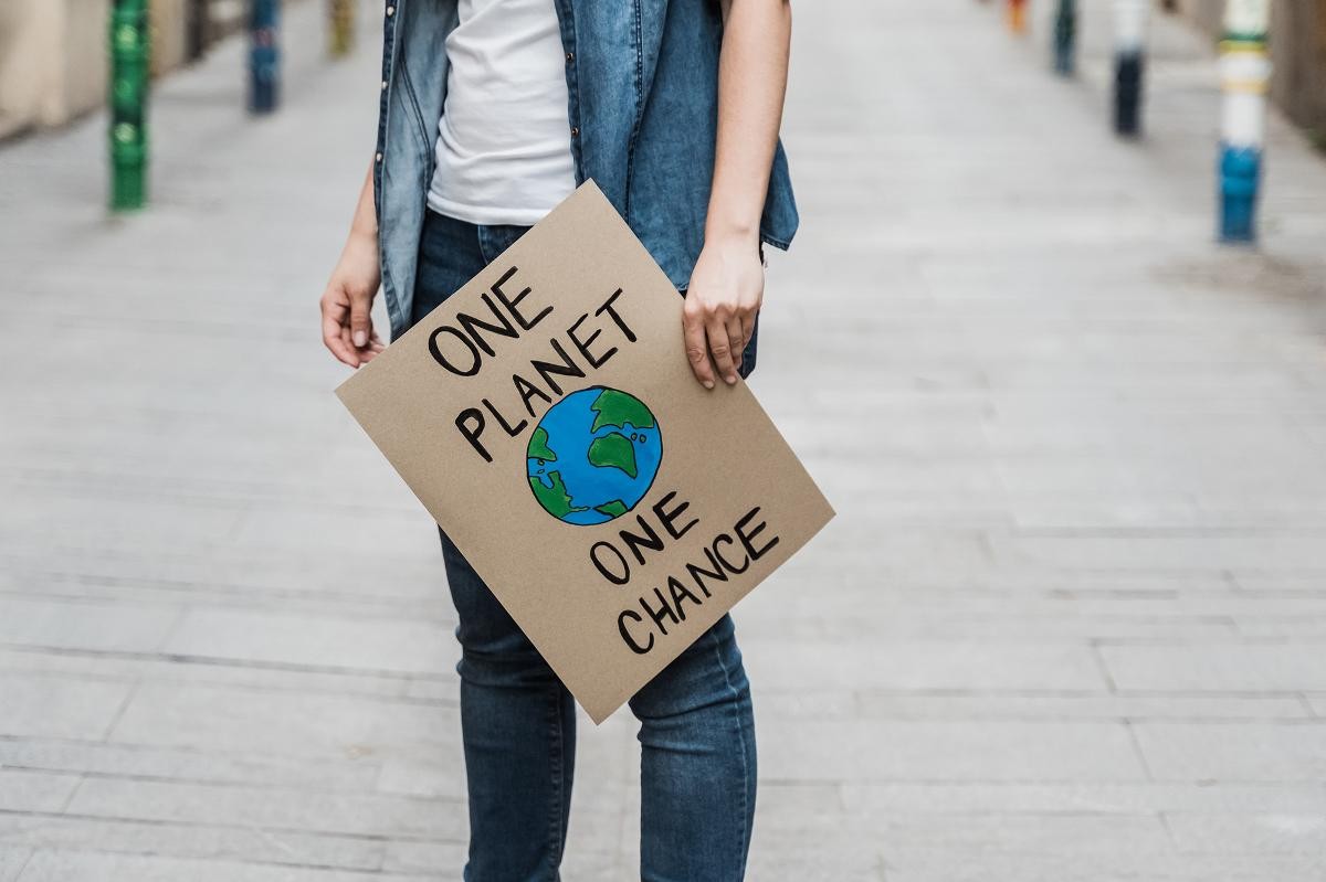 Person, die Plakat hochhält "One Planet, one chance!