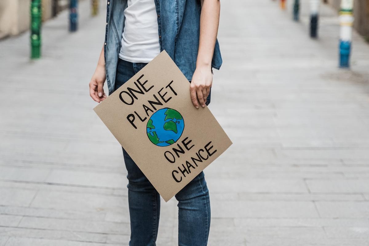 Person mit Schild One Planet One Chance
